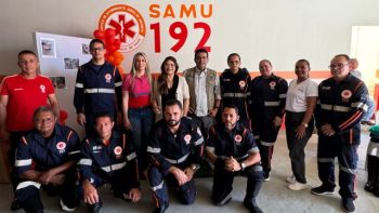 A imagem mostra uma equipe do SAMU 192 de Correntina, composta por profissionais do serviço de urgência e emergência. Estão em pé, com o prefeito Mariano e a secretária de saúde (mulher de óculos claros, entre a mulher de rosa e o prefeito). No centro, o comandante e equipe do SAMU, com uniformes, participam de um evento de valorização e entrega de novos equipamentos e ambulância.