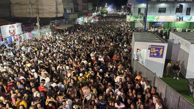 Multidão ocupa avenida durante o Carnaval de Correntina à noite, com grande concentração de foliões em frente a comércios e estruturas de camarote, sob iluminação pública e clima festivo.
