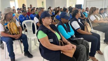 Participantes de uma capacitação promovida pela Prefeitura de Correntina acompanham uma apresentação em um auditório. Entre o público estão agentes comunitários de saúde, agentes de combate às endemias e outros profissionais da rede municipal, sentados em cadeiras brancas e atentos às orientações.