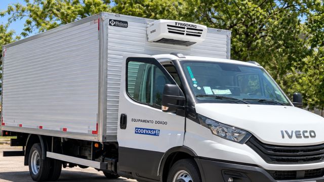 Caminhão frigorífico branco da Iveco, visto de frente e pela lateral, com baú refrigerado, porta do motorista aberta e identificação da Codevasf.
