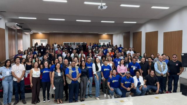 Grupo de participantes reunidos em auditório durante congresso de educação física realizado em Correntina, com profissionais do esporte e educação posando para foto coletiva.
