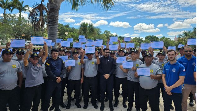 Grupo de vigilantes do município reunidos ao ar livre, segurando certificados de conclusão de curso, durante evento de entrega de uniformes e capacitação promovido pela Prefeitura de Correntina.