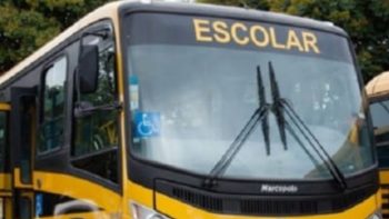 Ônibus escolar amarelo estacionado, com a palavra “ESCOLAR” em destaque na parte frontal superior. O veículo possui símbolo de acessibilidade no para-brisa, indicando adaptação para pessoas com deficiência.
